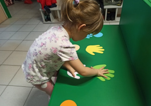 Dziewczynka dopasowywuje swoje dłonie do szablonu dłoni.